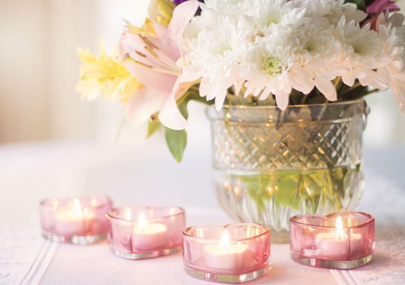 Soft white chrysanthemum bouquet beside glowing pink tea lights, cremation services Moore, OK