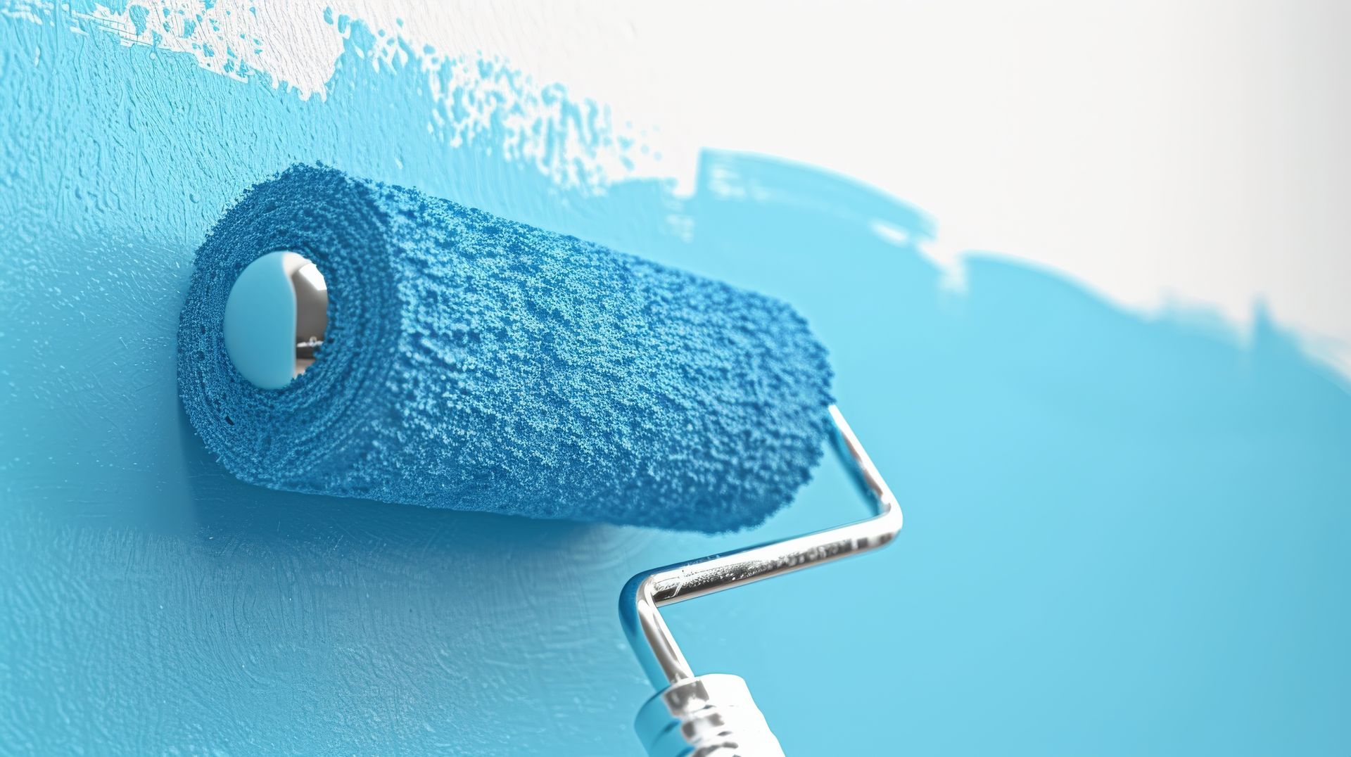 A blue paint roller is being used to paint a wall.
