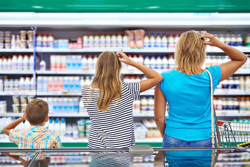 A family of consumers at the supermarket scratching their heads while looking at the huge variety of products on the shelf