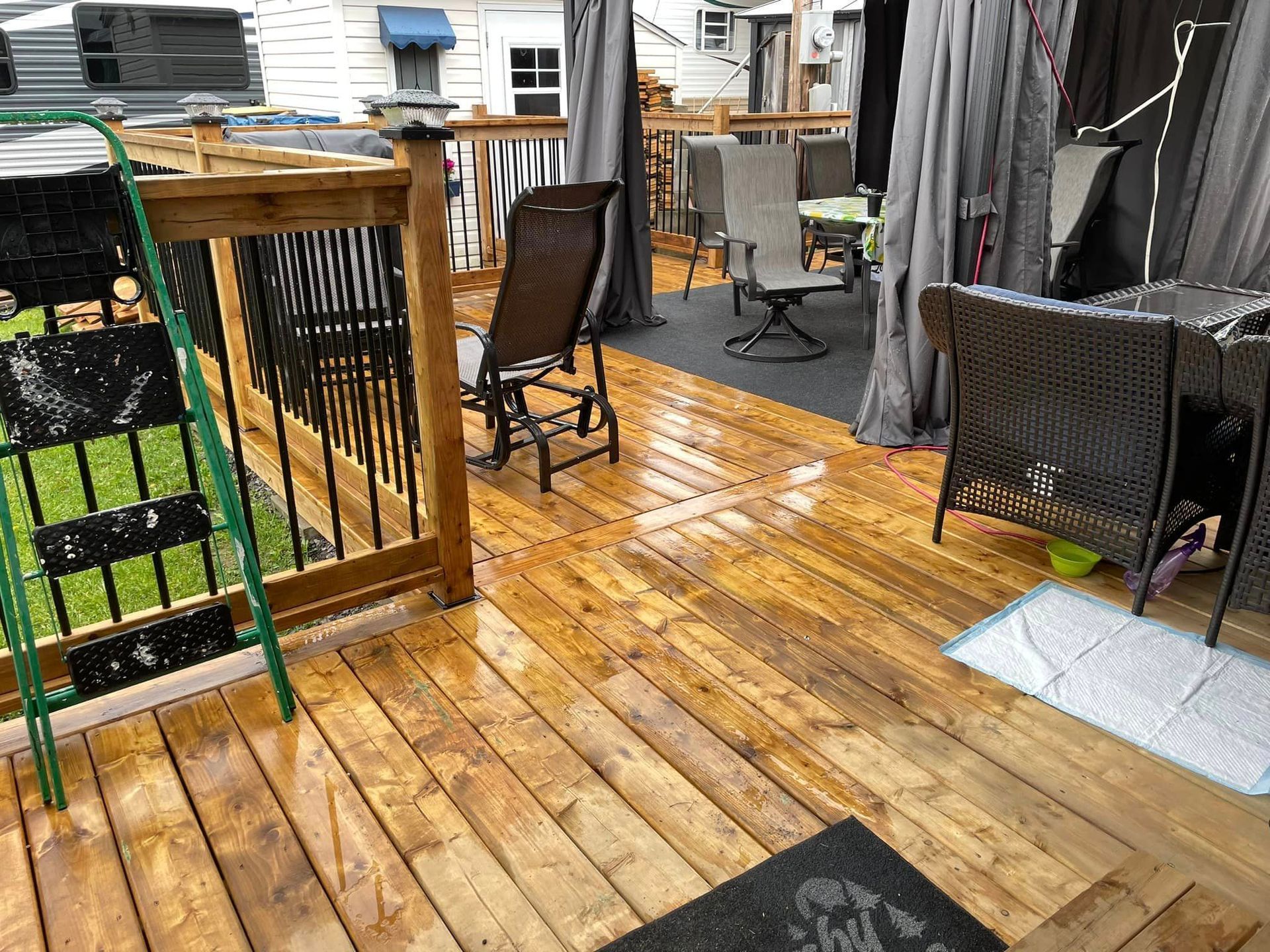 Une terrasse en bois avec une échelle et des chaises dessus.