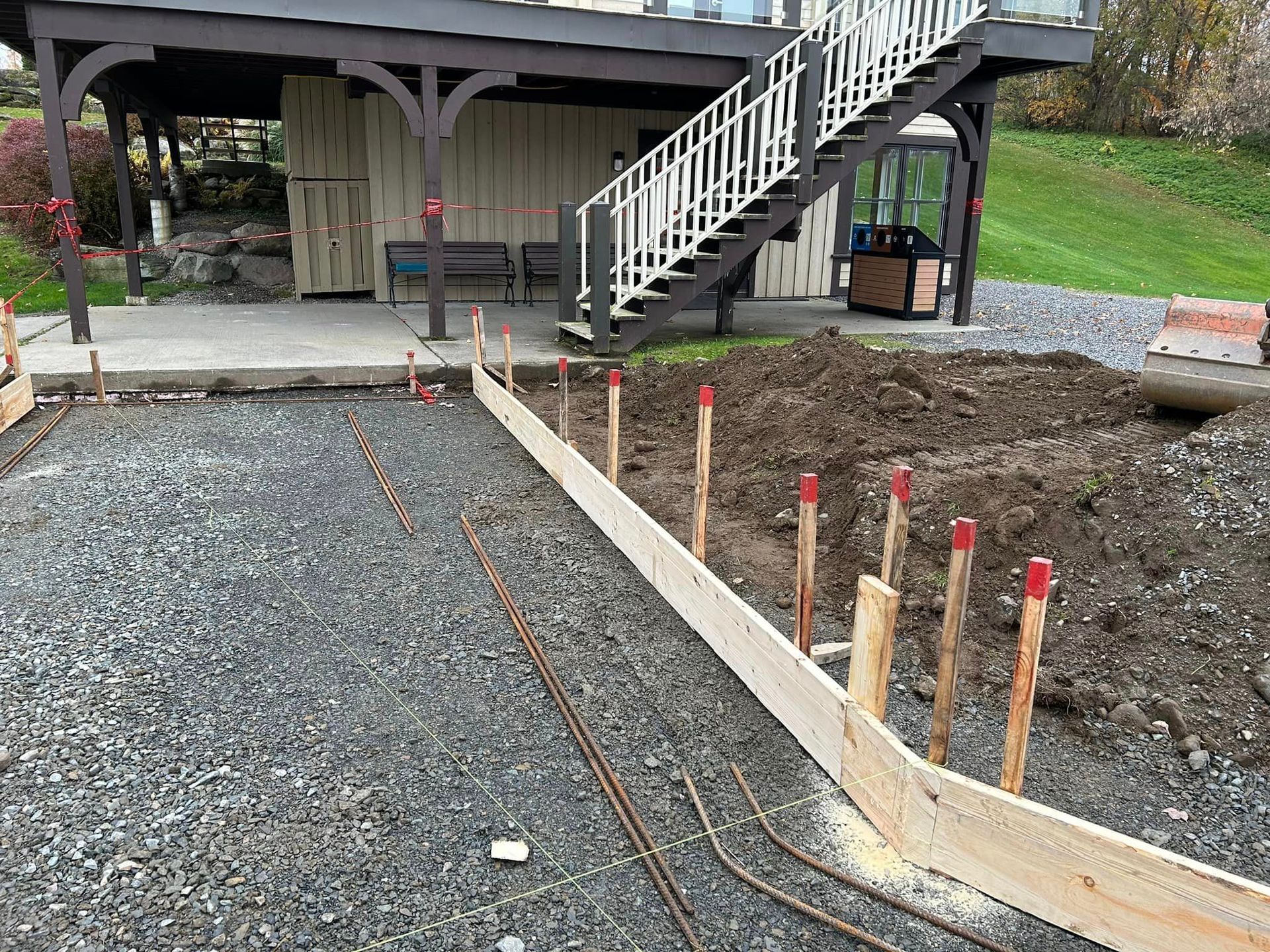 Une allée en béton est en cours de construction devant une maison avec des escaliers.