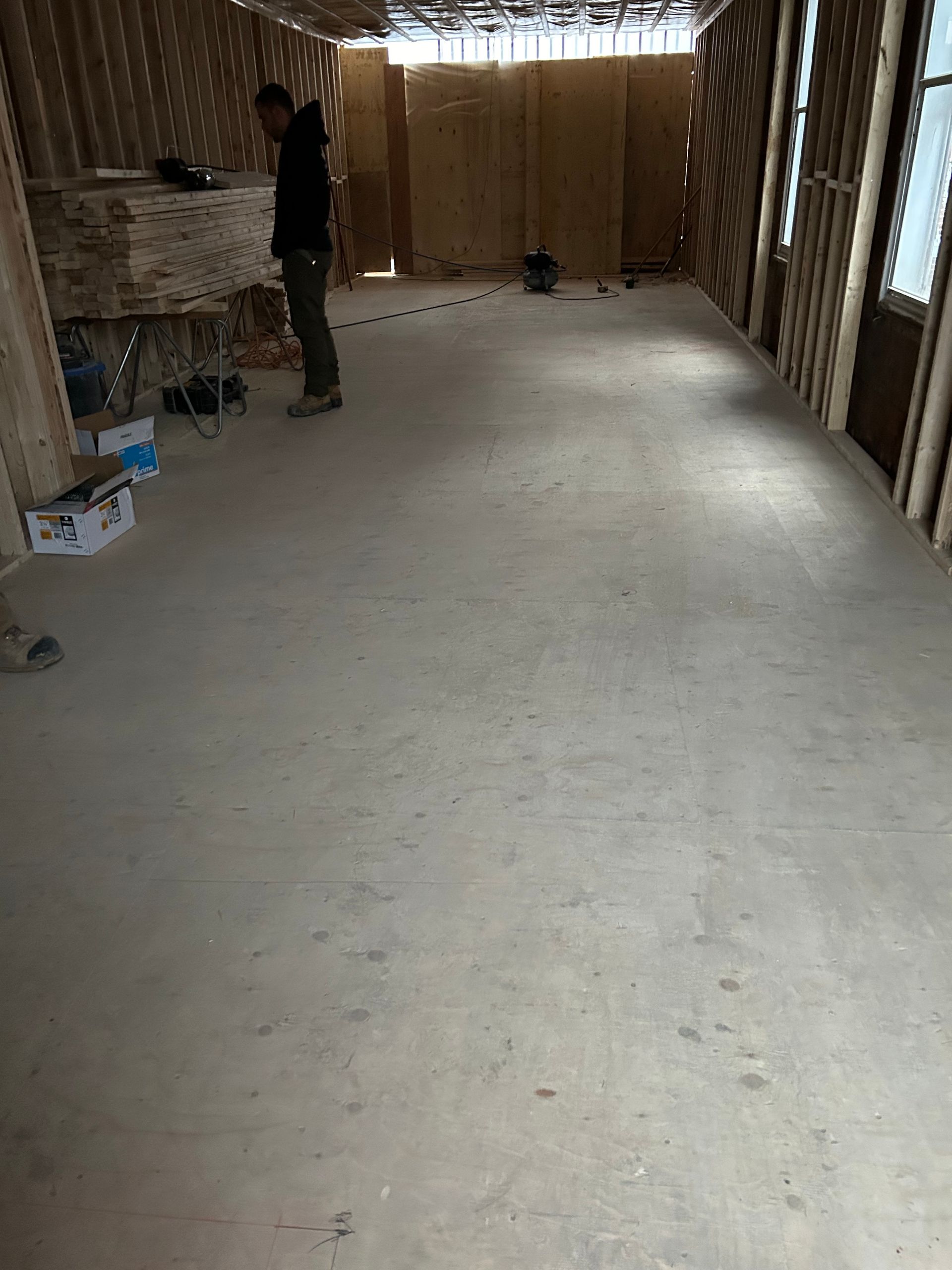 Un homme se tient debout dans une pièce vide avec un sol en béton.