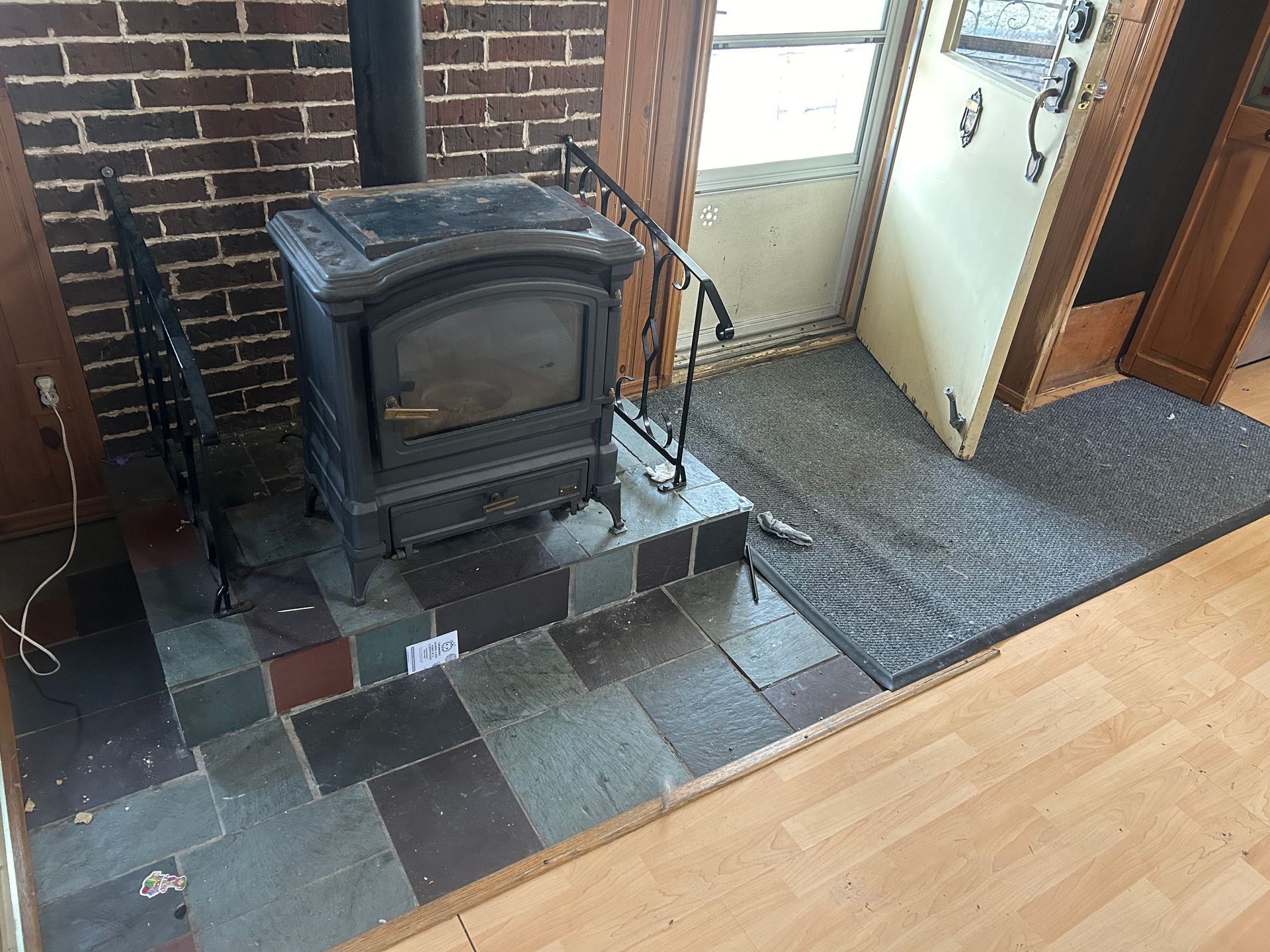Un poêle à bois est installé dans un salon à côté d'un mur de briques.