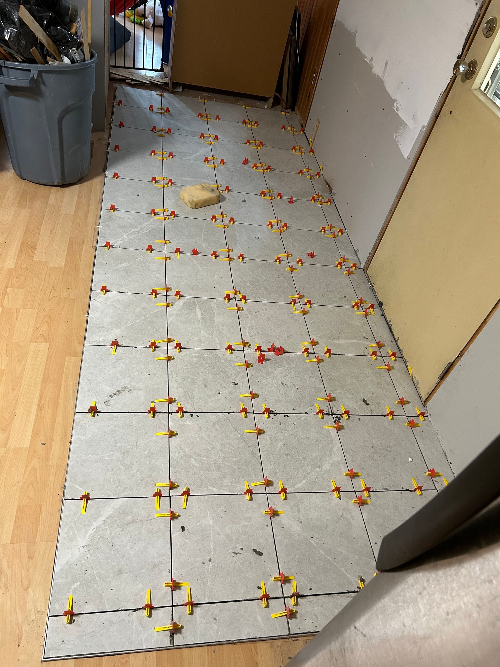 Un sol avec beaucoup de carrelage et une poubelle en arrière-plan.