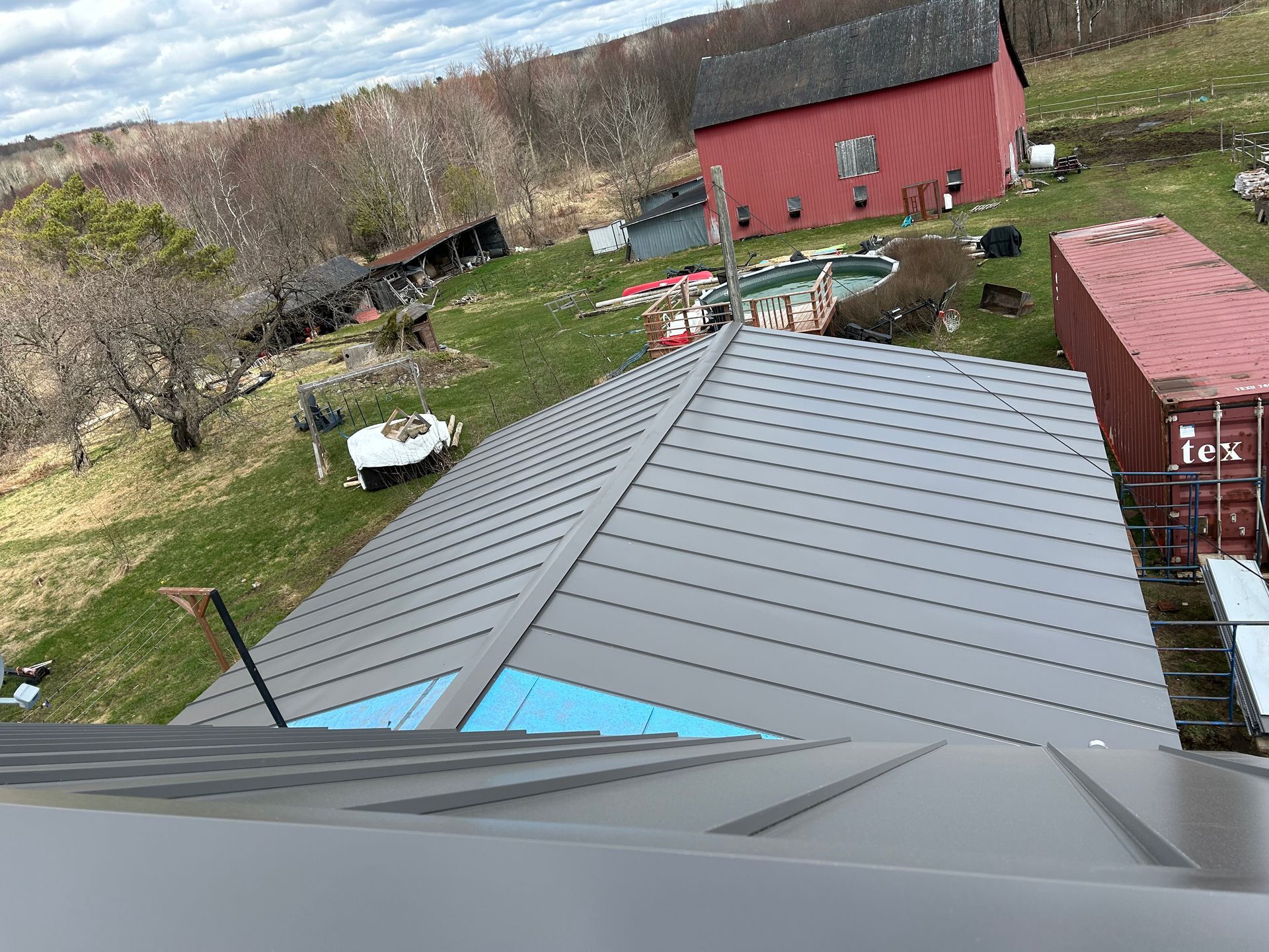 Une vue aérienne d'un toit avec une grange rouge en arrière-plan.