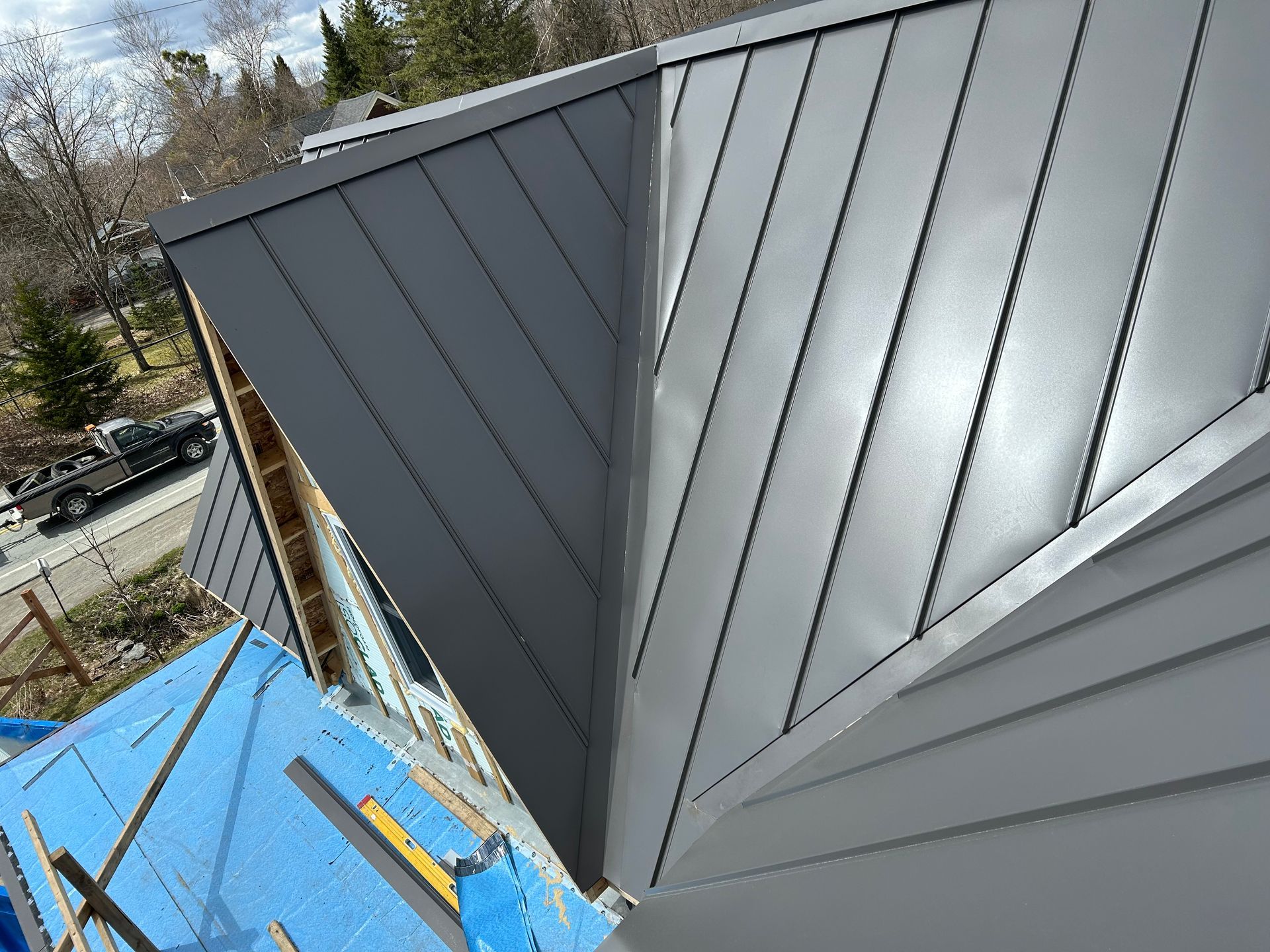 Un toit en métal gris est en cours d'installation sur une maison en construction.