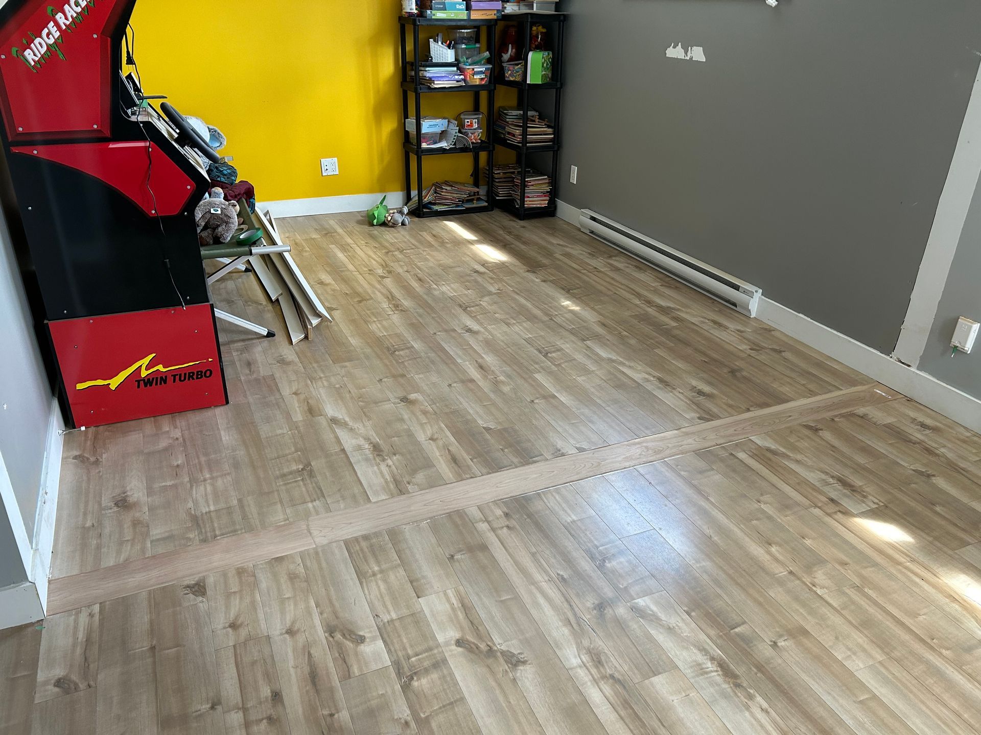 Une pièce avec un plancher en bois et une console de jeux vidéo.
