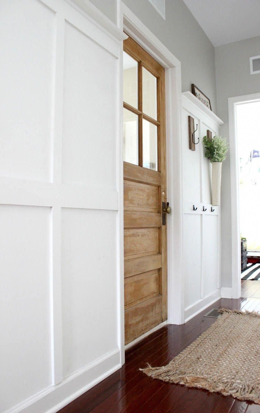 A hallway with a wooden door and a rug on the floor.