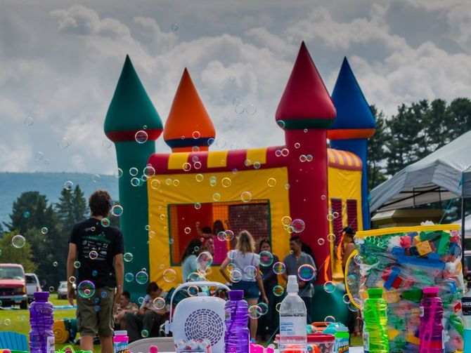 Children playing at a colorful inflatable bounce house with cone towers outdoors under cloudy skies