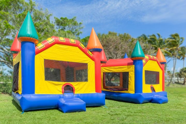 Colorful inflatable bounce houses on a grassy lawn under a blue sky