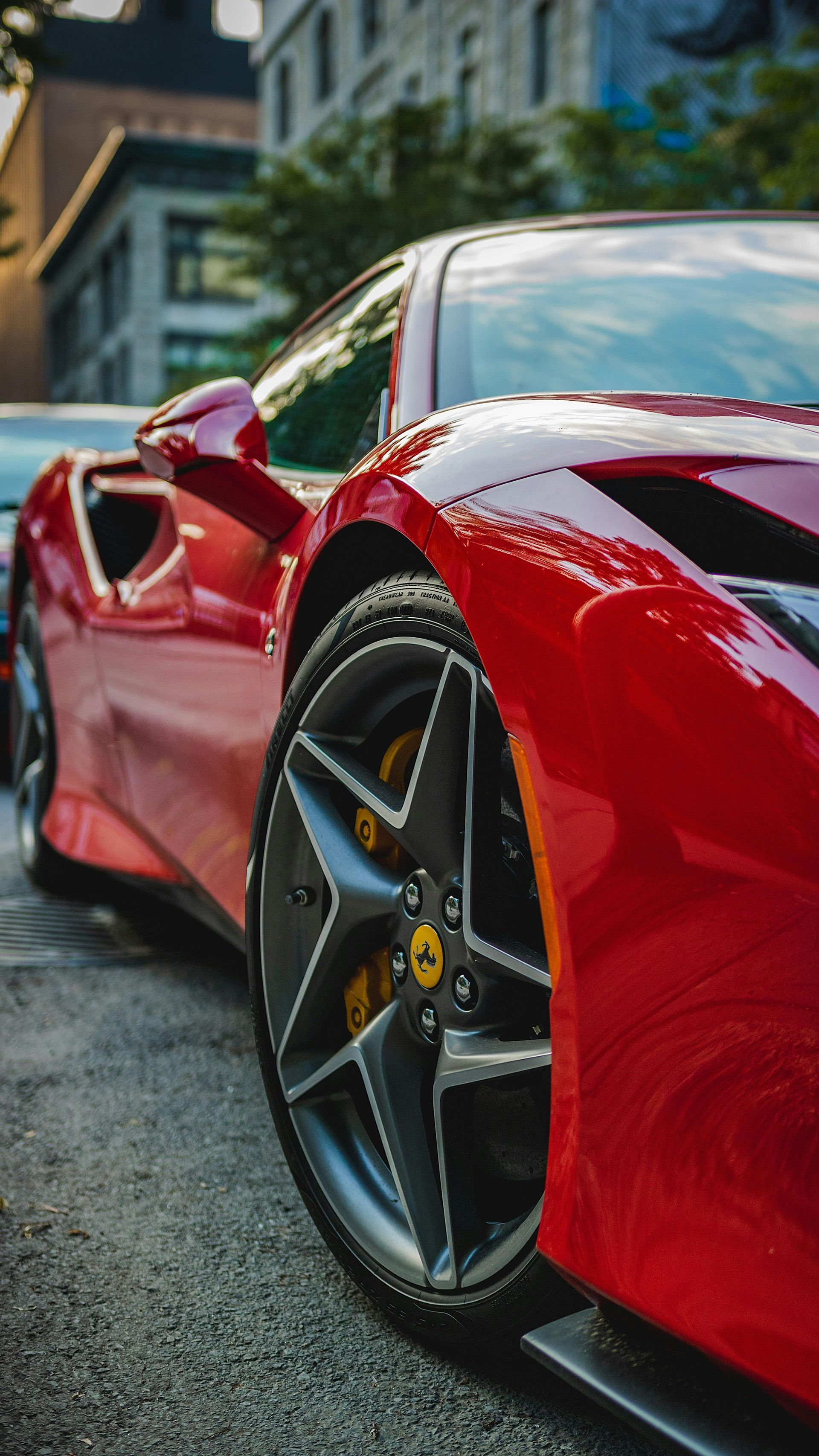 Red Ferrari sports car parked on a city street, close-up of the front wheel.