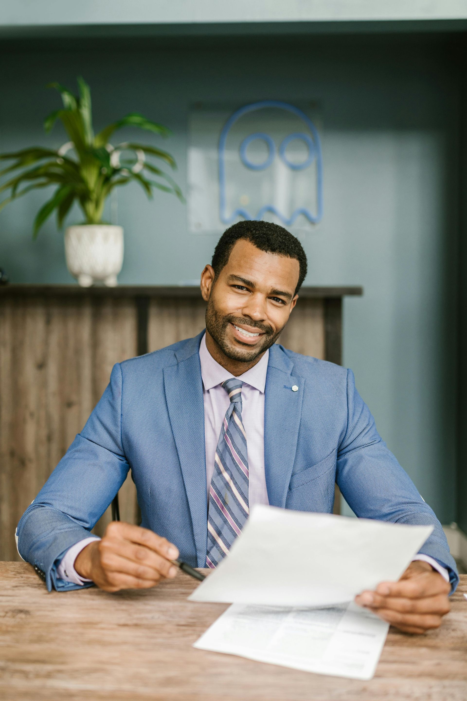 A man in a suit and tie is sitting at a table holding a piece of paper.