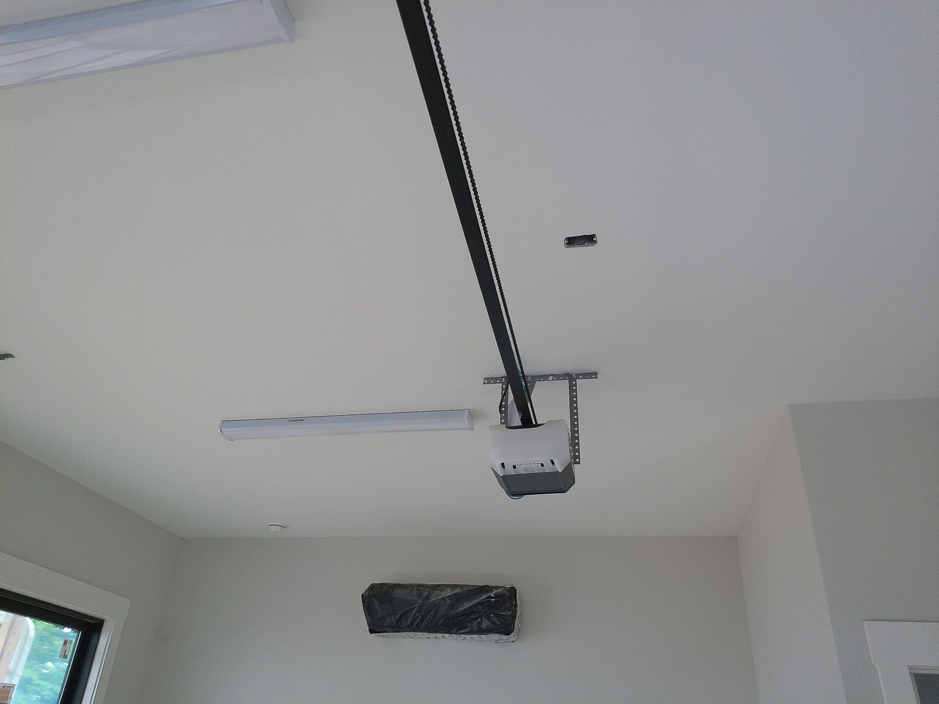 A garage door opener is hanging from the ceiling in a room.