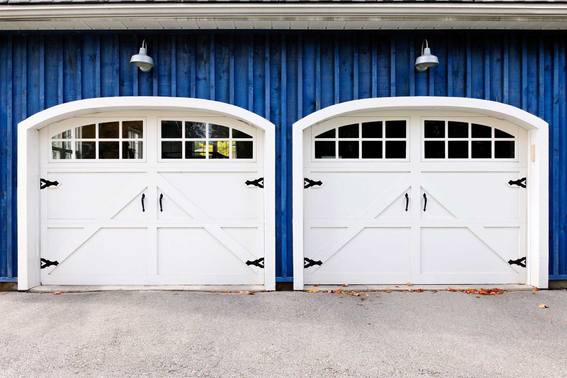 There are two white garage doors on a blue building.