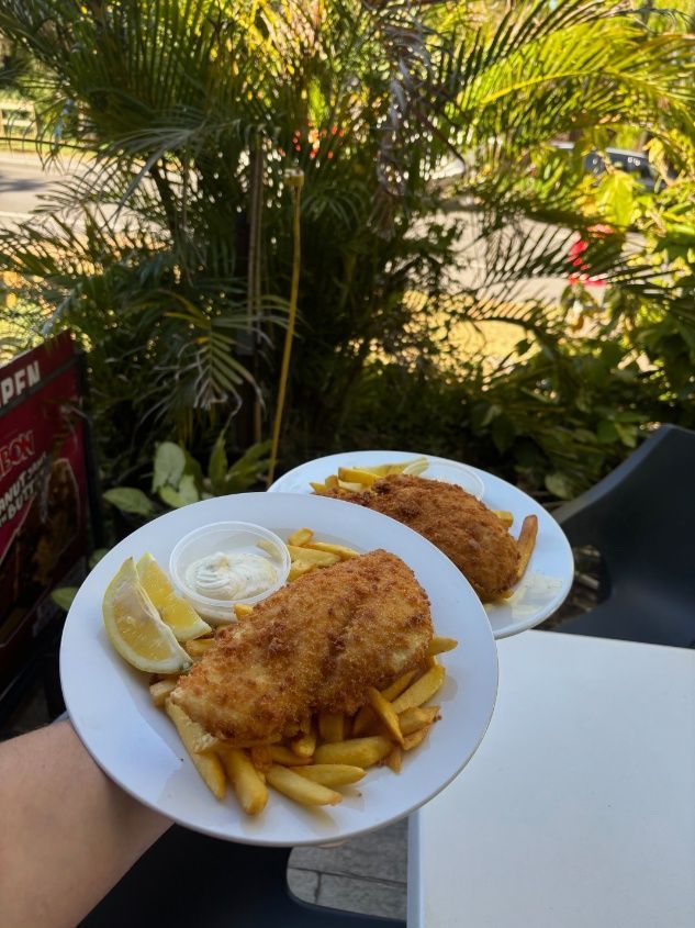 A Hand Holding Two Plates Of Fish And Chips — Kinka Kippa in Kinka Beach