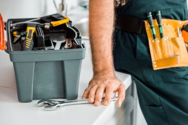 Technician with toolbox and wrench on countertop during professional home repair service.