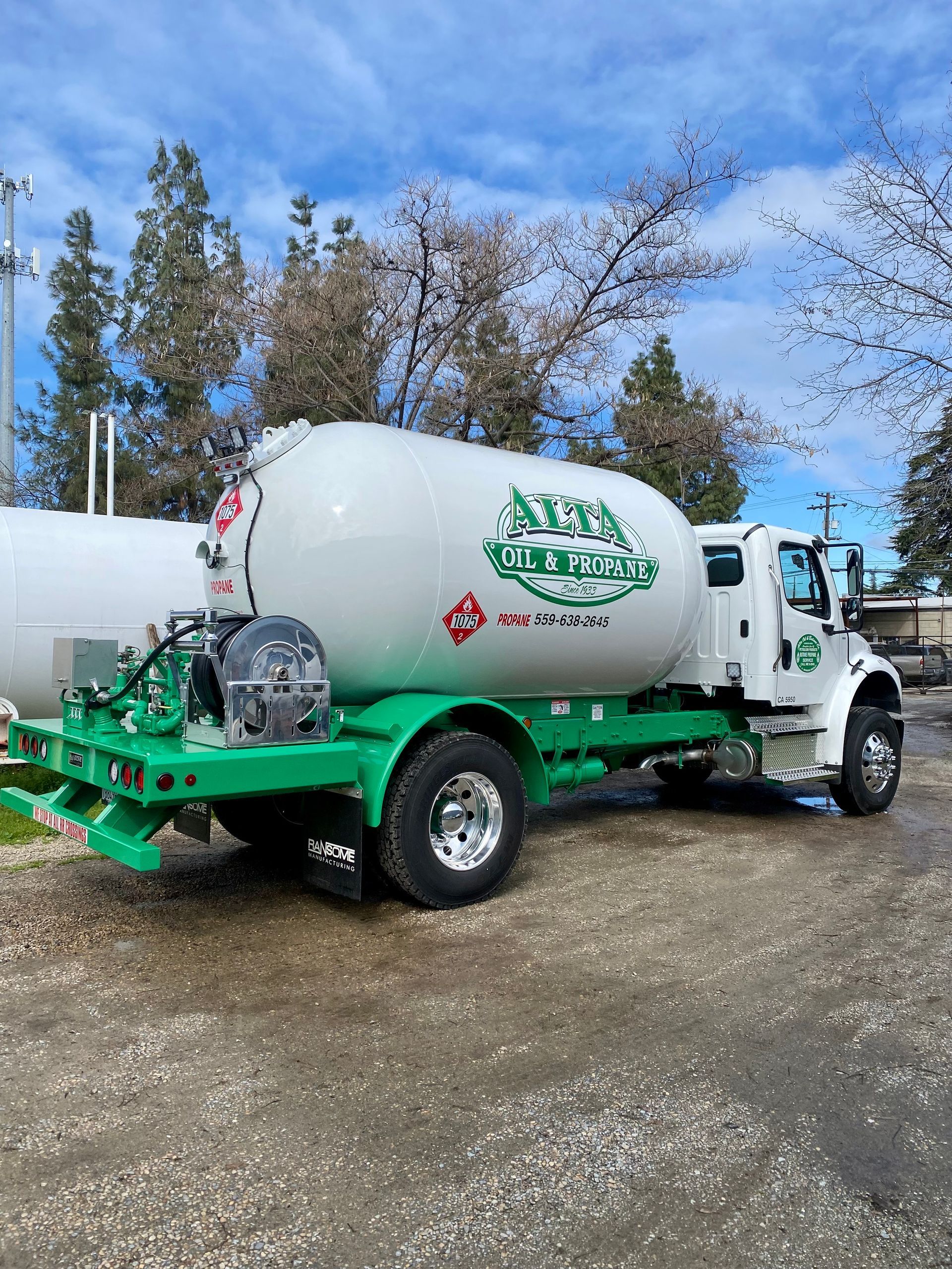 Green and white propane truck with the company logo parked outside.