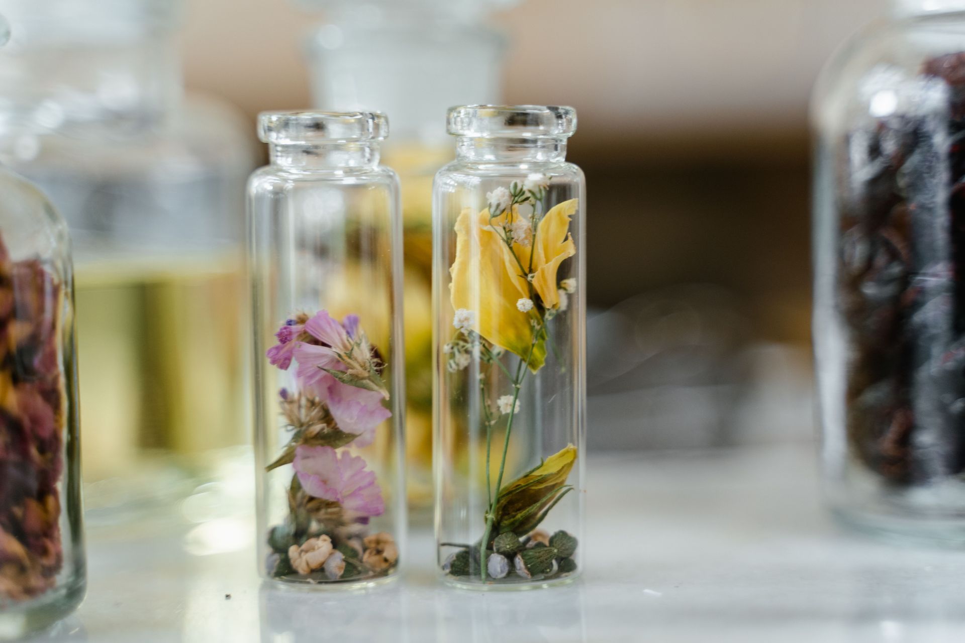 Amber herbal oil bottles and glass jars of dried herbs on a wooden table with lavender sprigs