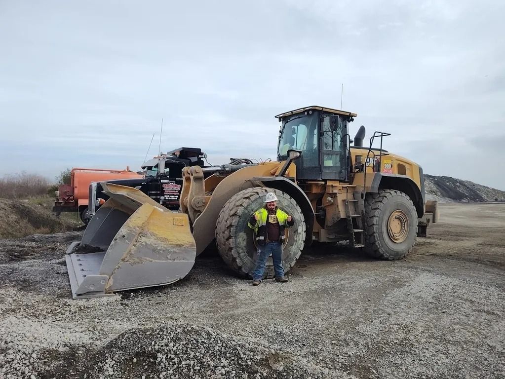 Yellow loader dumping gravel into white dump trucks