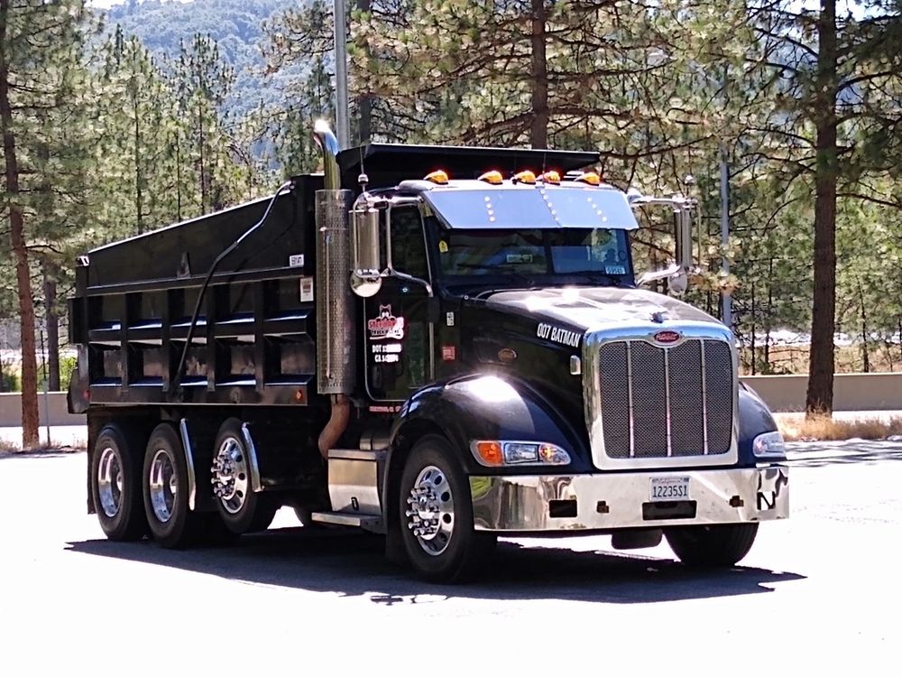 Black dump truck parked outdoors on a sunny day