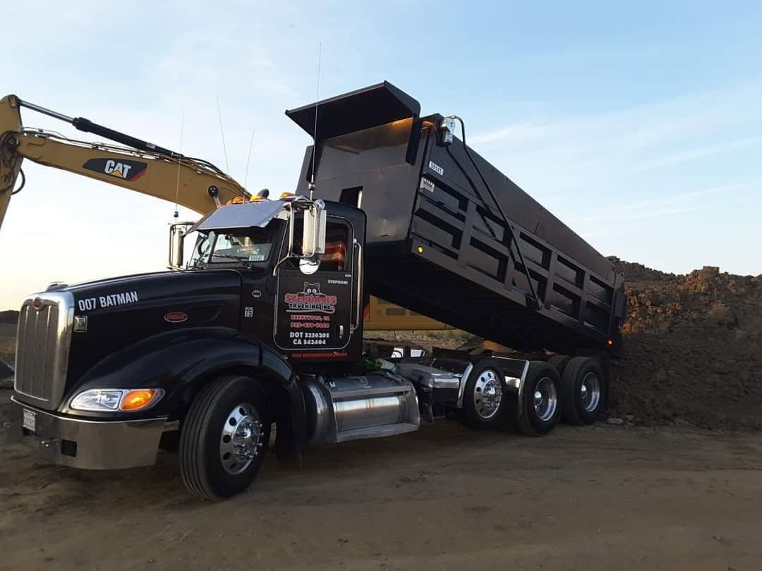 Yellow loader dumping gravel into a red dump truck at a construction site