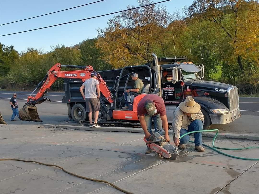 Yellow excavator loading dirt into a red dump truck, under a blue sky