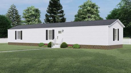 A white mobile home with black shutters is sitting on top of a lush green field.