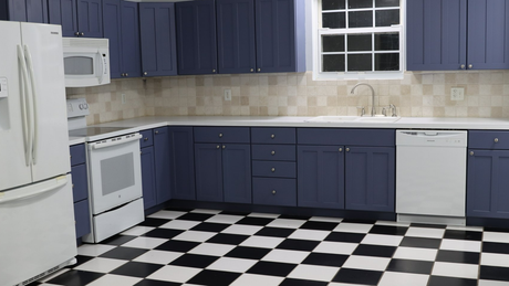 A kitchen with blue cabinets and a black and white checkered floor