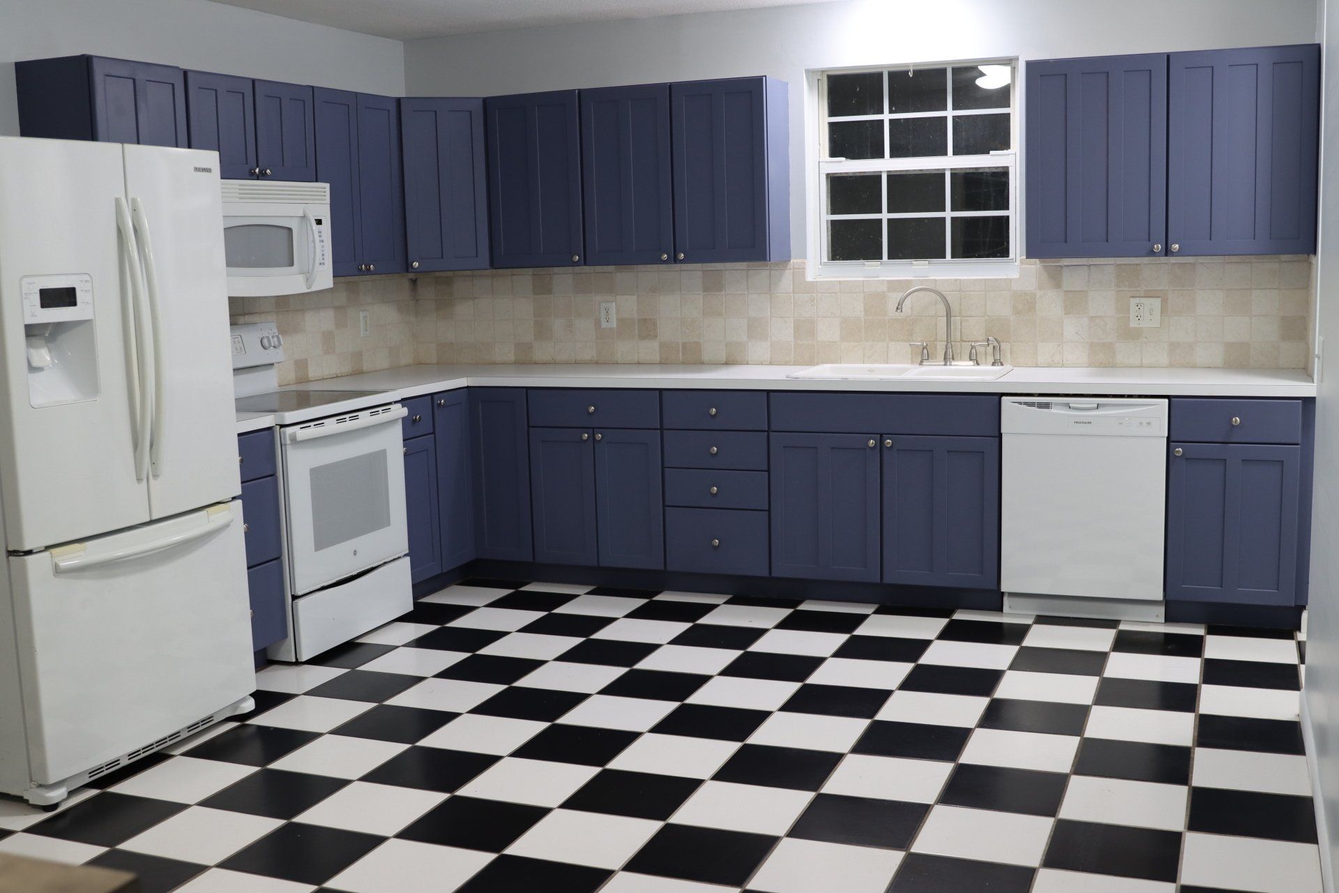 A kitchen with blue cabinets and a checkered floor