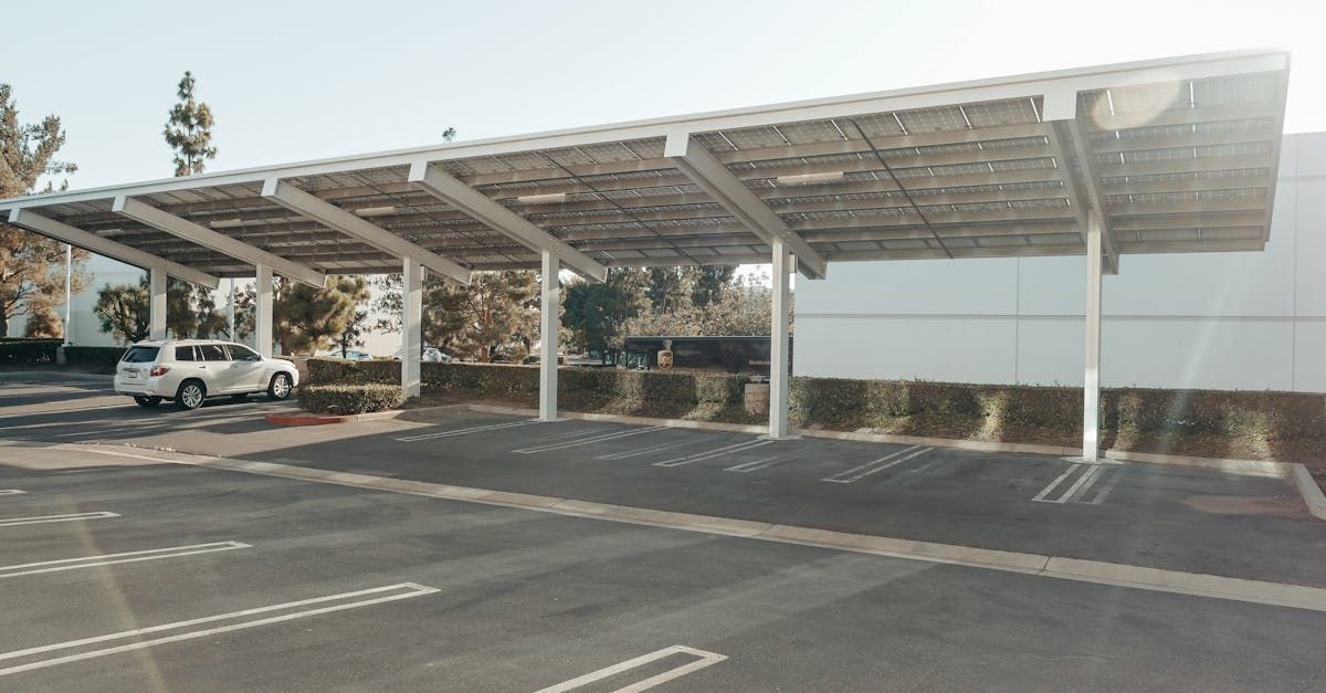 A car is parked under a canopy in a parking lot.