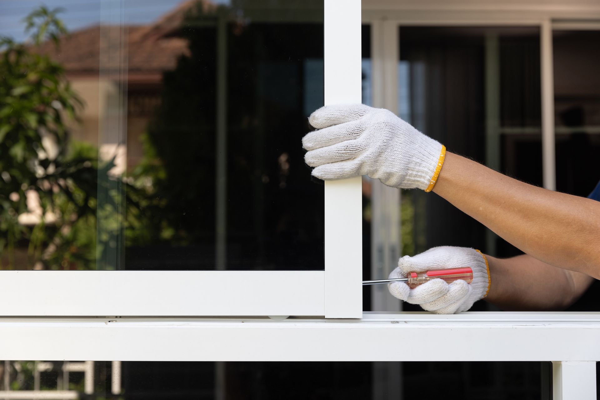 A man is fixing a window with a screwdriver.