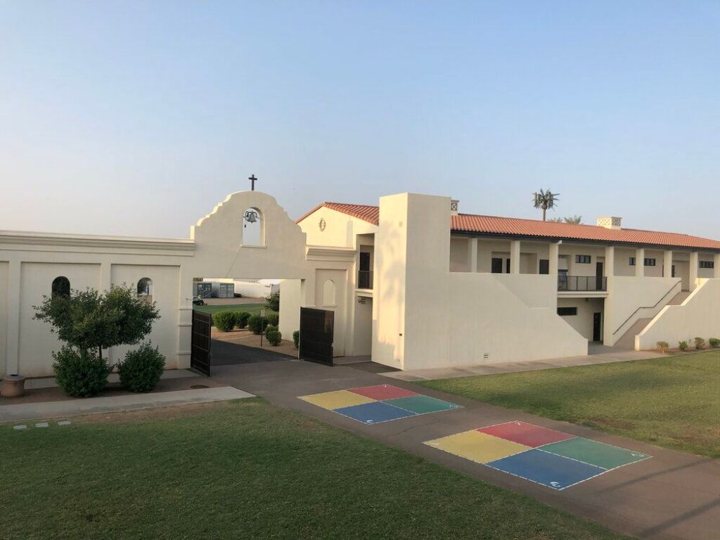 Apartment courtyard with white buildings, red roofs, grass, and a colorful tiled walkway