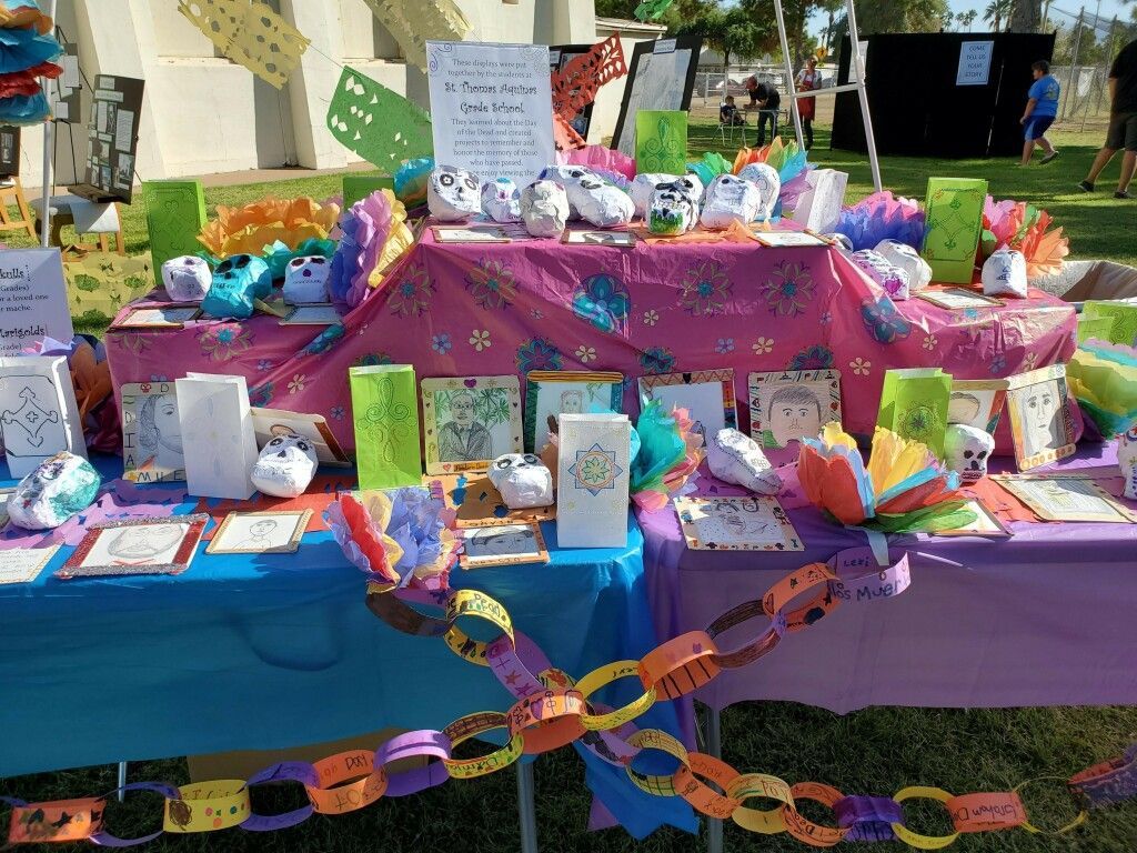 Colorful memorial table with candles, flowers, cards, and paper chains outdoors in a park