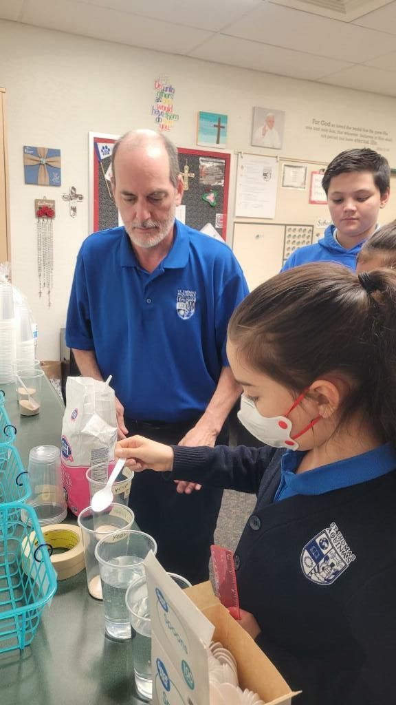 People in a classroom science lab measuring liquid into a beaker during an experiment