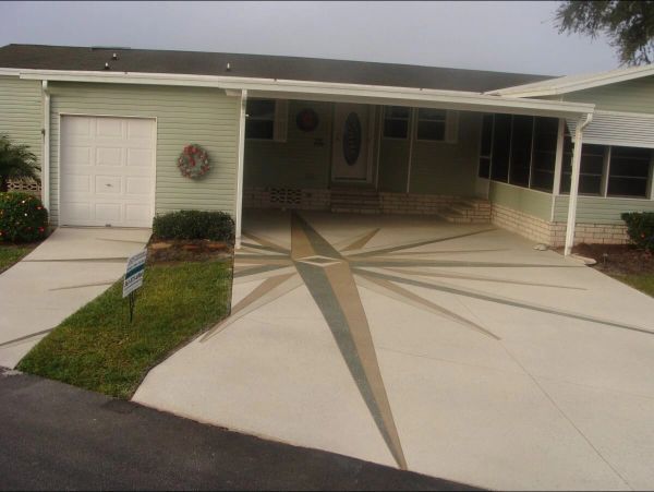 A light green house with a decorative compass rose design in the driveway.