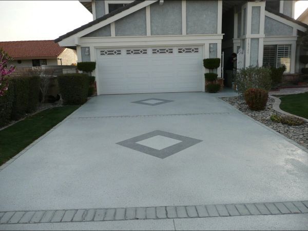 Driveway of a house with diamond-shaped concrete patterns; light gray with decorative border.