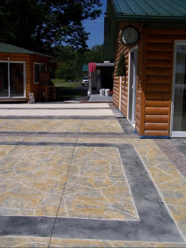 Log cabin with decorative concrete patio in shades of gray and yellow.