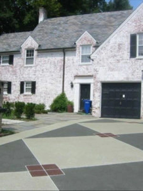 White brick house with a patterned concrete driveway and black garage door.