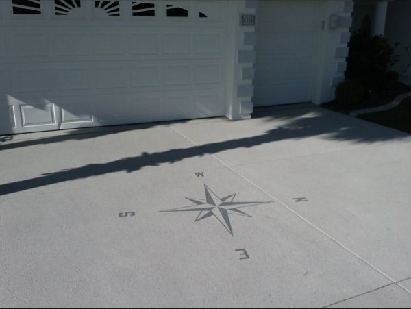 Concrete driveway with a compass rose design near a garage.