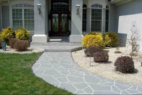 Stone pathway leads to a house entrance, with shrubs and landscaping.