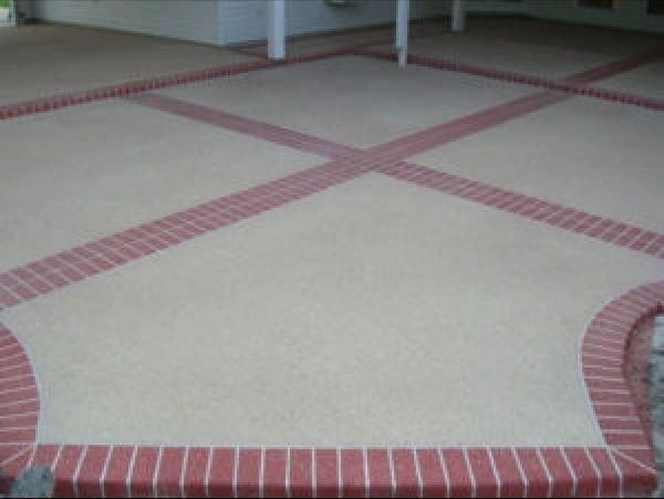Brick-bordered concrete patio with cross design and light-colored center, viewed from above.