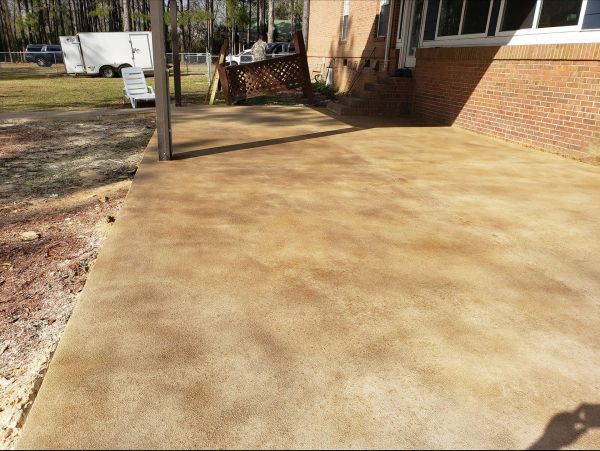 Brown-stained concrete patio next to a brick house.