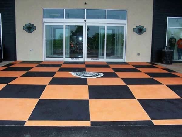 Checkerboard patio in orange and black leading to glass doors of a building with the Harley-Davidson logo in the center.