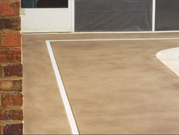 Brick wall next to a tan-colored concrete surface marked with white lines, possibly a sports court.
