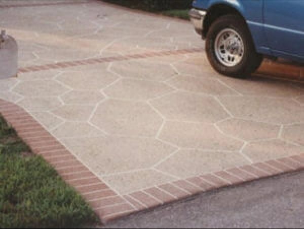 A driveway with a stone pattern and a brick border, partially occupied by a blue truck.