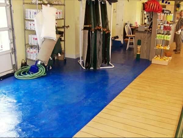 Blue painted floor transitions to wood flooring inside a shop, a man stands in the background.