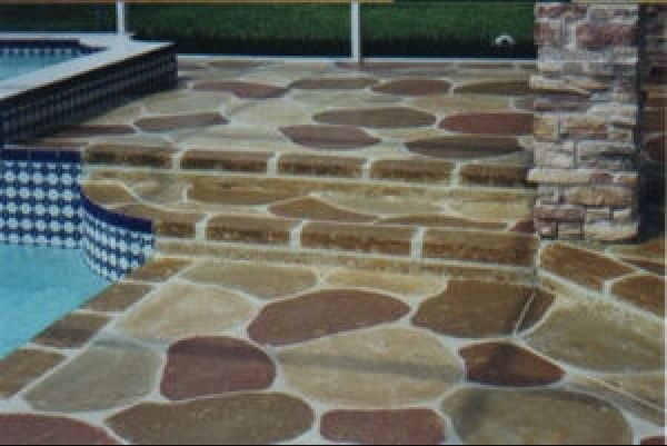 Stone-patterned concrete pool deck with steps, in shades of brown, tan, and gray.