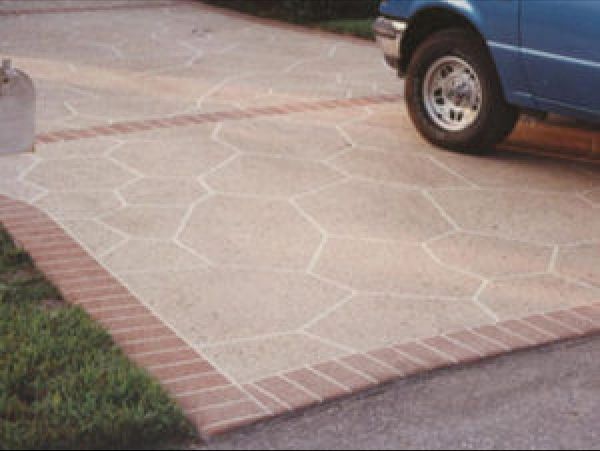 Driveway with flagstone pattern and brick border; blue car parked.