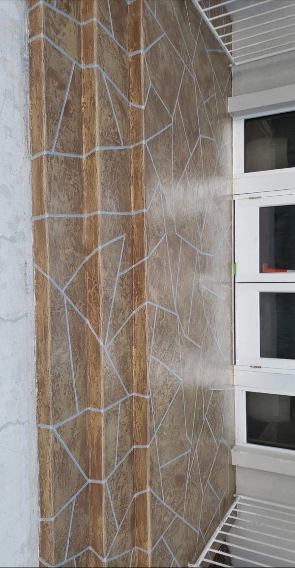 Brown and tan patterned wall tiles next to a white shelving unit.