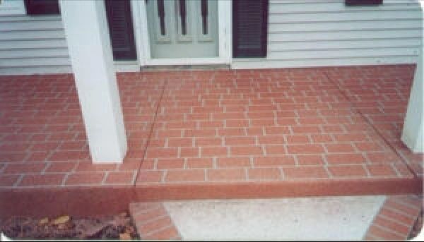 Red brick-patterned concrete porch with white columns and a white door.